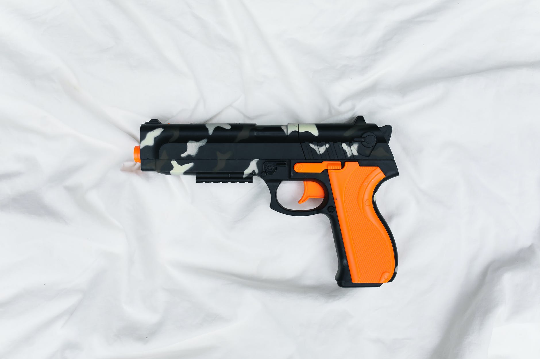 black and orange semi automatic pistol on white textile