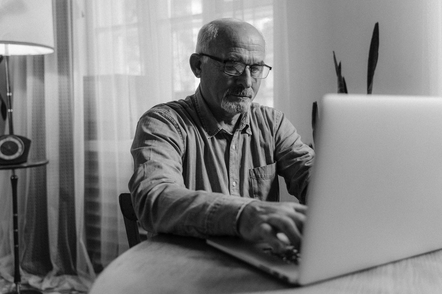 Middle-aged white man sitting on the table using laptop