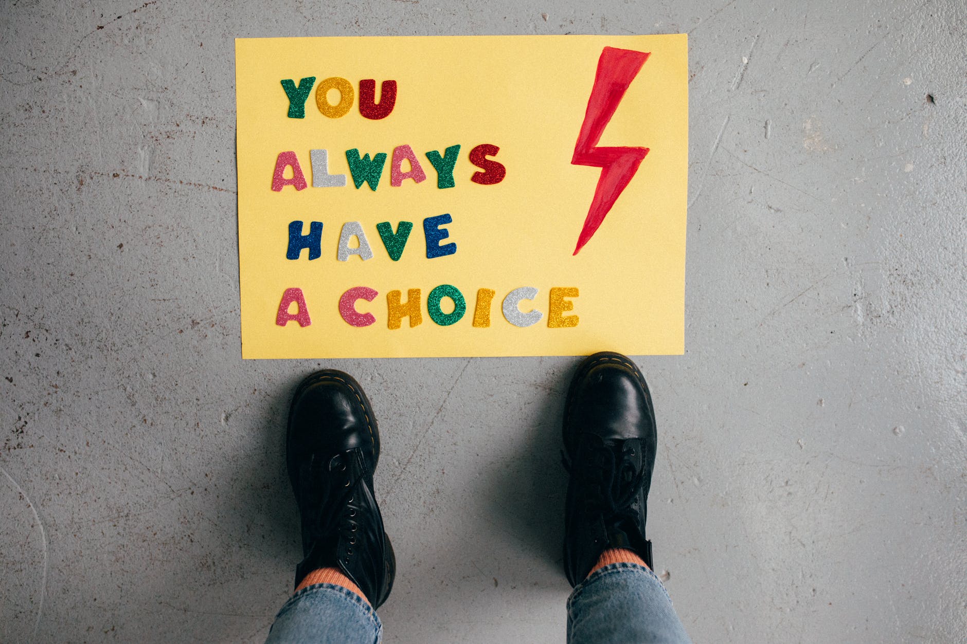 person in blue denim jeans and black leather shoes standing on white and yellow sign abortion rights