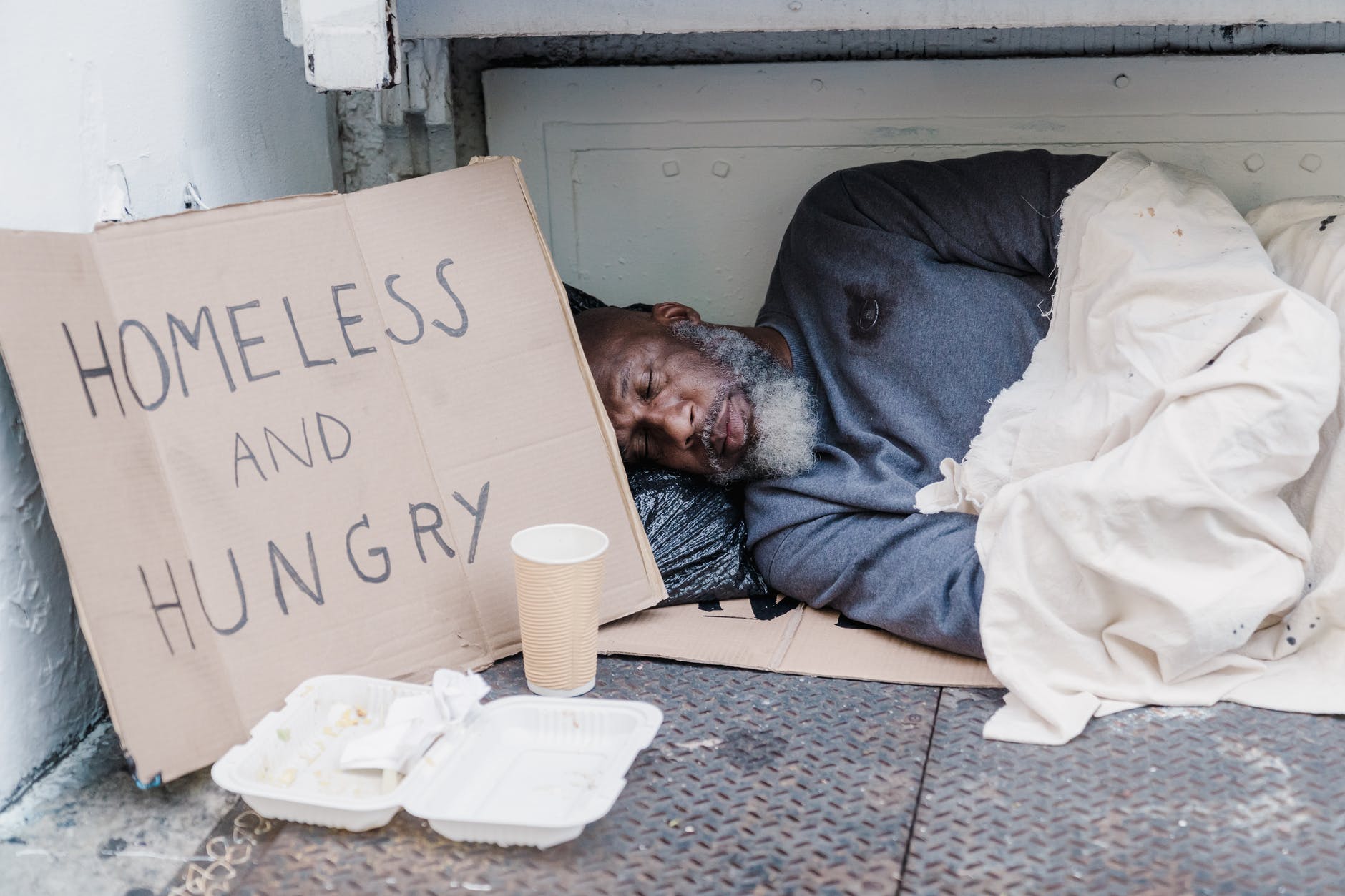 Ashamed to be british photo of a homeless man sleeping near a cardboard sign.