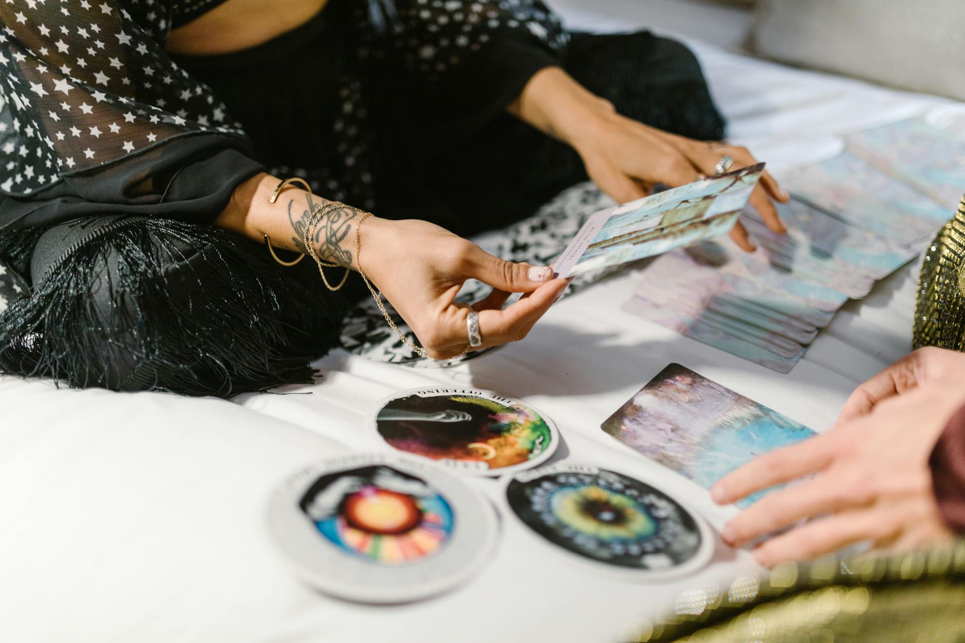woman sitting on a bed holding a card tarot creators to watch