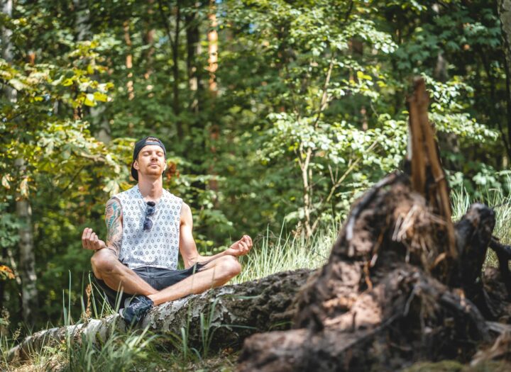 man meditating on a tree log